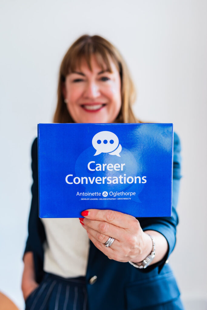 Antoinette Oglethorpe smiling holding a purple Career Conversations Toolkit that reads 