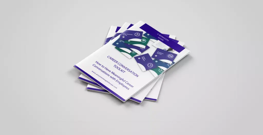 A stack of "A Manager’s Guide To Career Conversations" booklets, with a purple and white abstract design on a light grey surface—a digital resource for managers.