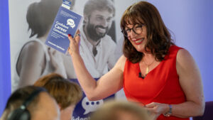 Antoinette Oglethorpe in a red dress holds up her best selling book titled 