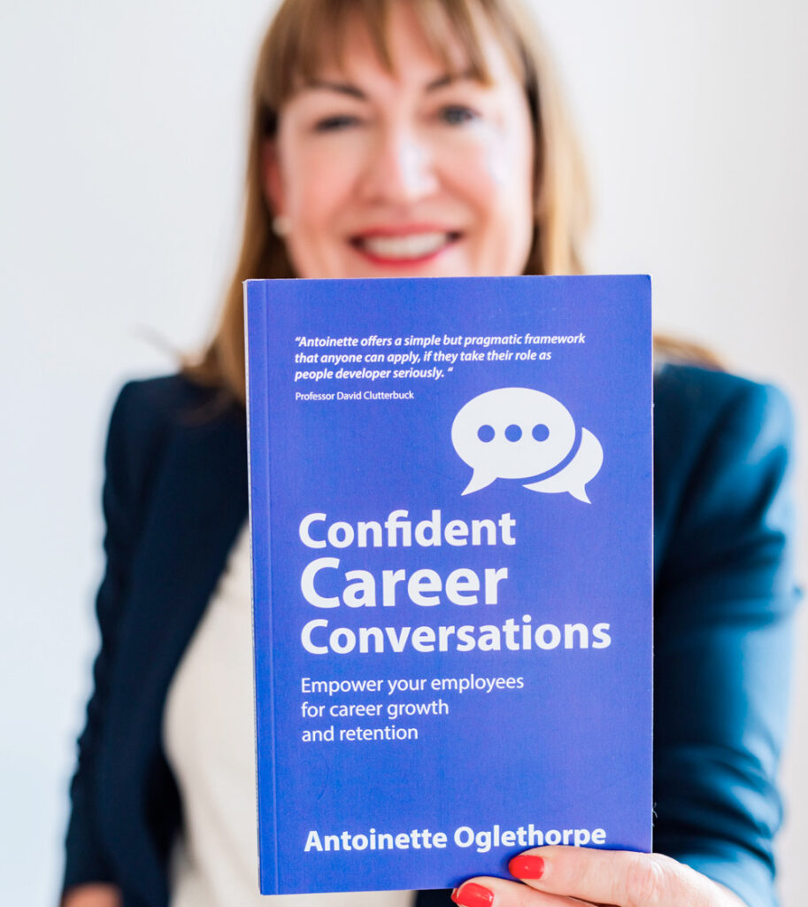 Antoinette Oglethorpe in a blazer holds up her book 