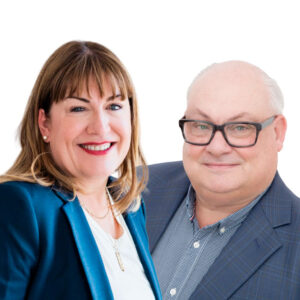 Antoinette Oglethorpe and Mark McKergow wearing business attire and smiling; Antoinette has shoulder-length brown hair and a blue blazer, while the Mark has glasses, short grey hair, and a checked jacket. Both are pictured against a white background. in t6he promotional bannewr for the webinar Solutions Focus and Mentoring